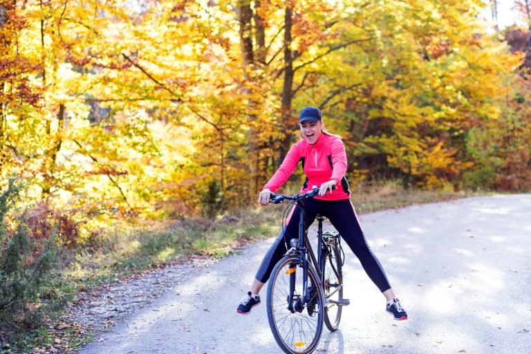 11-18-Fysieke activiteit reduceert bij vrouwen de pijnsensitiviteit_744005770 Sportieve vrouw op de fiets die door bewegen haar pijn onderdrukt.