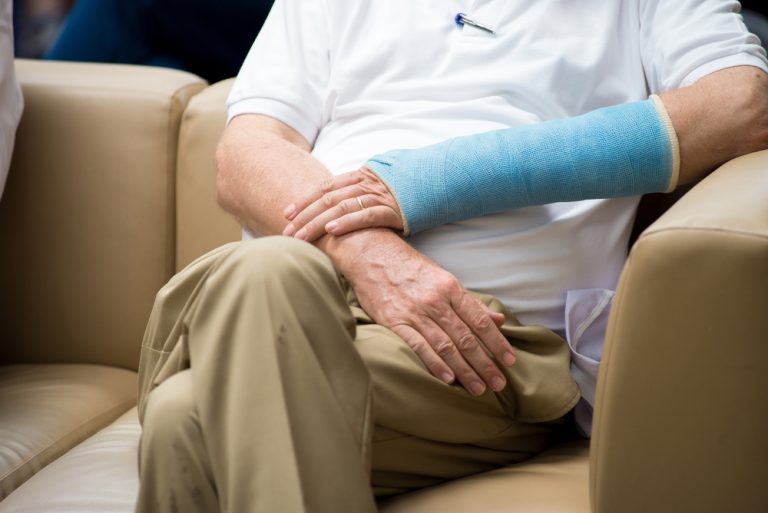 11-20-Graded Motor Imagery verbetert uitkomsten na polsfractuur_716821069 Man met polsfractuur zit op de bank en oefent via mentale verbeelding.