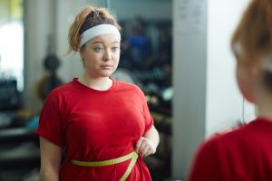 Sportieve obese vrouw meet omvang van haar buik.