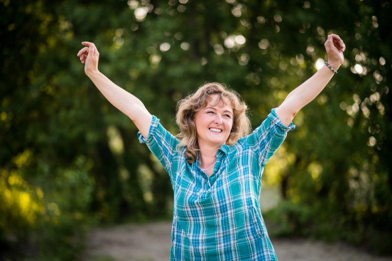 12-03-Fysiotherapeutische behandeling rotatorcuff ruptuur ook op lange termijn effectief _561308221 Vrouw die buiten blij en pijnvrij haar armen in de lucht heft.