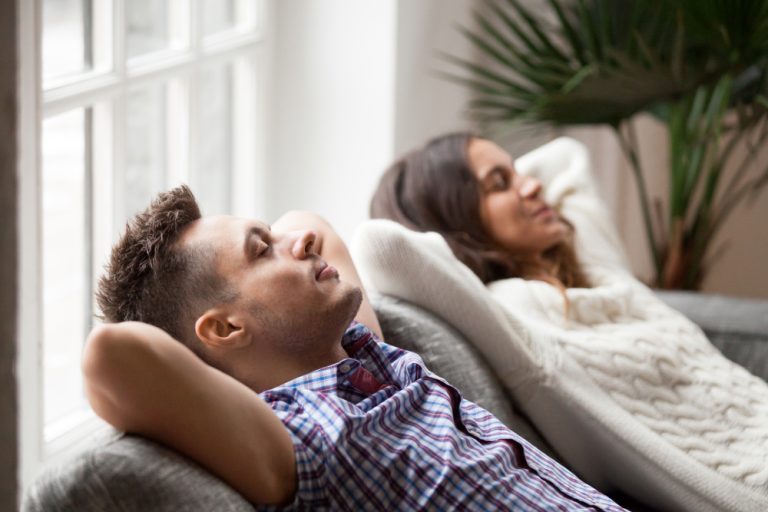 12-06-Adempauze verbetert het effect van traag diafragmaal ademen op de gezondheid_1038126100 Echtpaar doen samen thuis ademhalingsoefeningen.