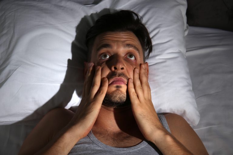 12-11-Zowel teveel als te weinig bewegen correleert met slaapproblemen_1163910922 Man ligt wakker in bed doordat hij te laat gesport heeft.