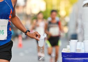 Hardloper pakt tijdens een wegwedstrijd en bekertje water.