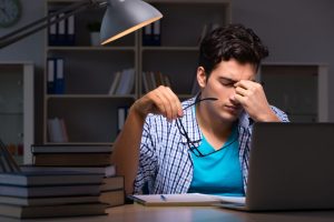 Zwaar vermoeide student 's avonds achter zijn laptop.