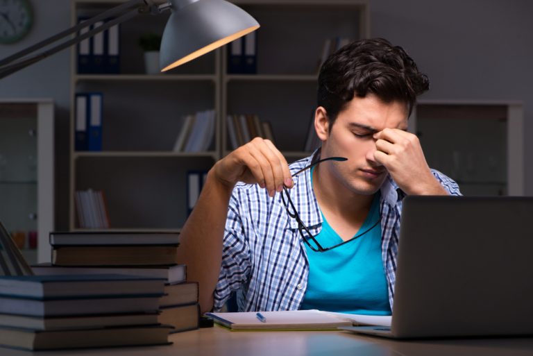 12-19-HRV-Biofeedback vermindert burnoutklachten bij studenten_1006900369 Zwaar vermoeide student 's avonds achter zijn laptop.