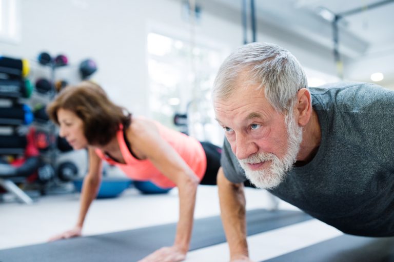 12-19-Langdurende fysieke activiteit vermindert globale pijn bij reumatoïde artritis Man en vrouw die fysieke training op de mat doen om pijn dragelijk te houden.