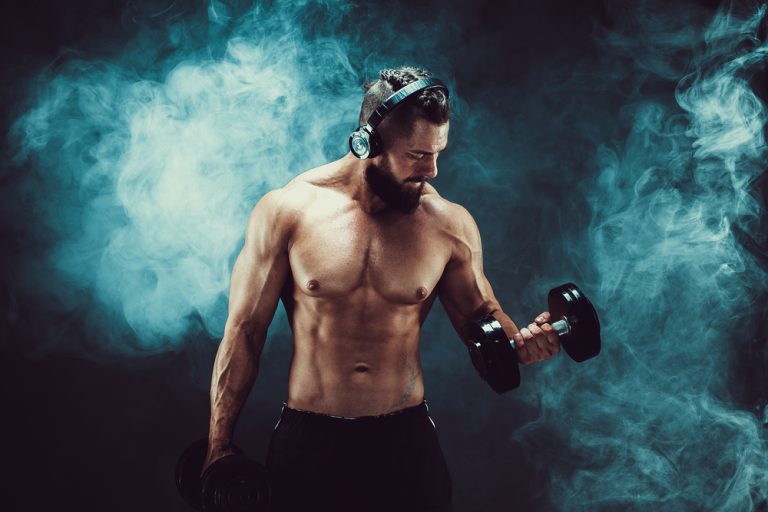 12-19-Muziek vermindert vermoeidheid tijdens oefenen_732455620 Bodybuilder traint zijn arm terwijl hij muziek op heeft.