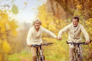 Twee opgewekte en zelfverzekerde ouderen sportief buiten aan het fietsen.
