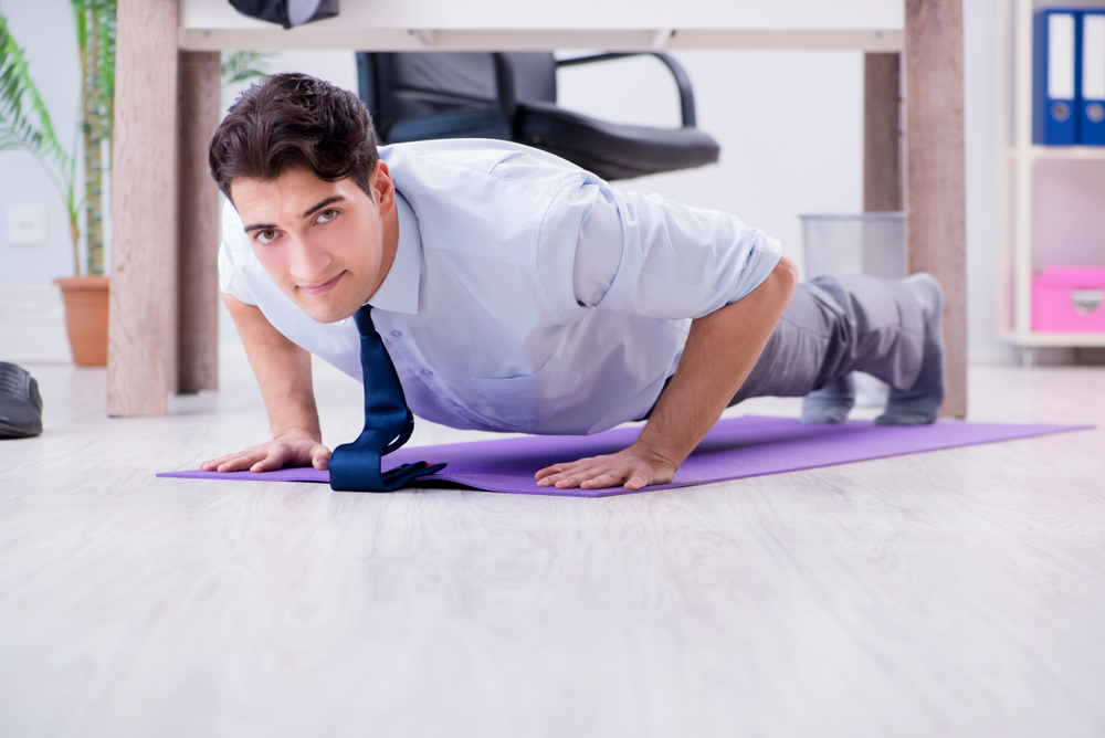 Man doet op zijn werk in de pauze push-ups en voorkomt daarmee rugklachten.