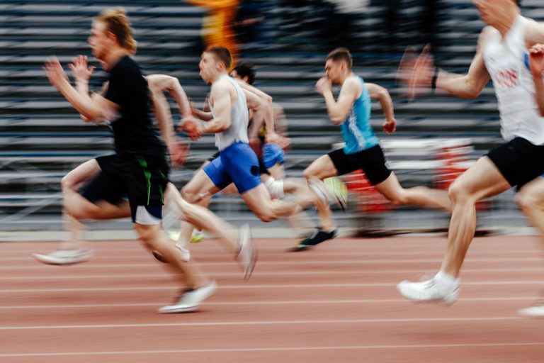13-02-Het verbeteren van de maximale snelheid_1107437372 Groep hardlopers op de atletiekbaan met hoog tempo.