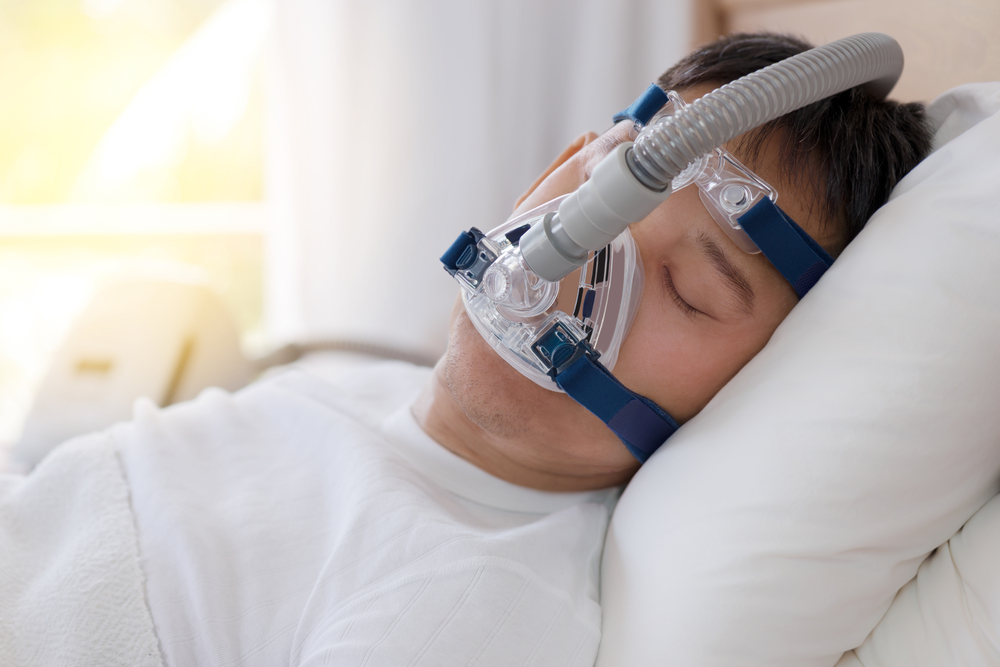 Patiënt met slaapapneu in bed met zuurstof masker op.