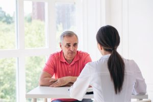 Fysiotherapeute in gesprek met een chronische pijnpatiënt over de nadelen van 'vechten tegen de pijn'