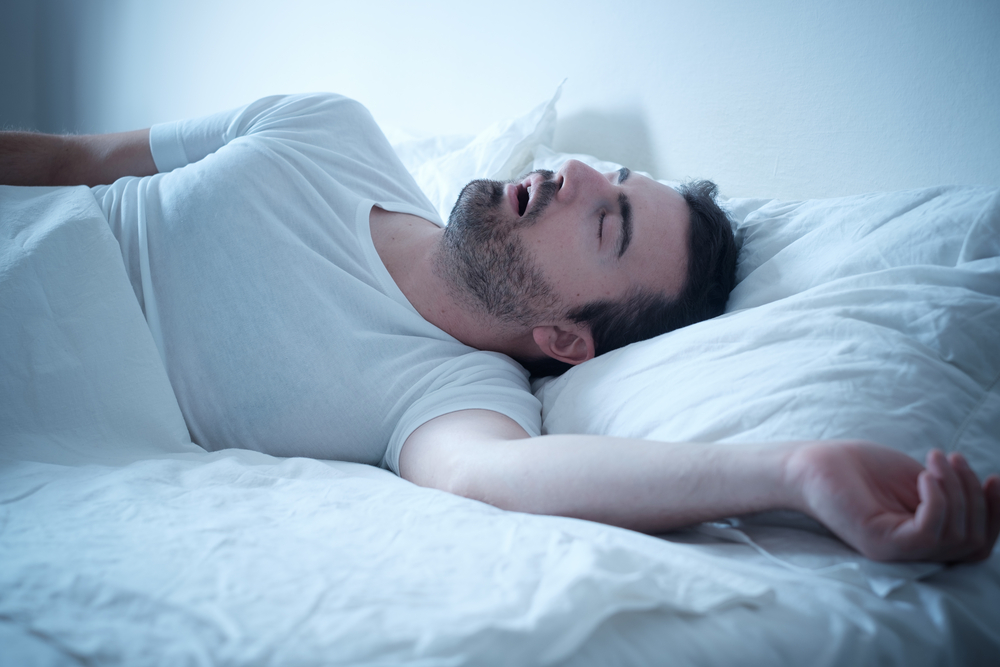 Man met slaapapneu in bed heeft baat bij ademoefeningen.
