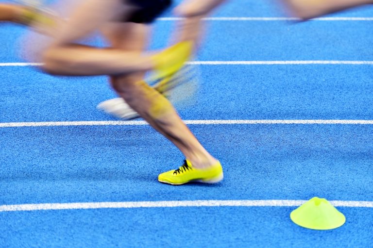 13-16-Overbelasting blessures bij hardlopers van verschillende niveaus_385506718 Afzet van de voet bij snelle hardloper op atletiekbaan.