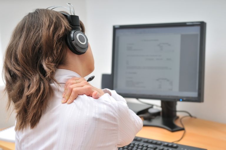 13-16-Trapeziusactiviteit tijdens beeldschermwerk_53621761 Jonge vrouw zit achter haar computer met pijn in de rechter trapezius.