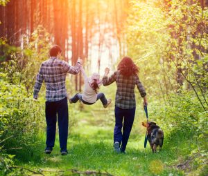 Ouders die speels hun kind 'slinger' tijdens zondagswandeling.