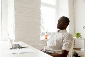 Man doet op zijn werk een ontspanningsoefening achter zijn laptop.