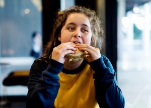 Adolescente eet hamburger.