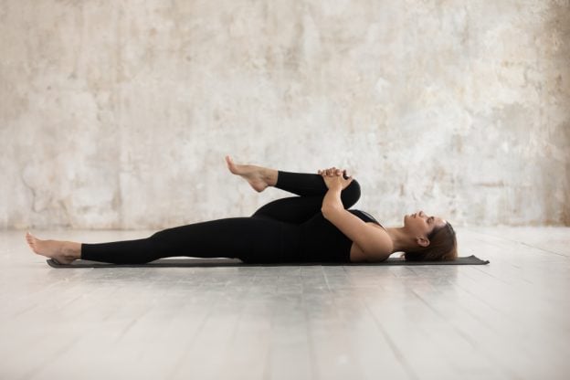 Vrouw in yogahouding op een mat, die mindfulness toepast voor het verlichten van rugpijn