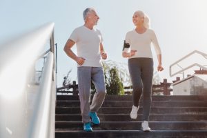 Twee sportieve ouderen lopen buiten de trap af.