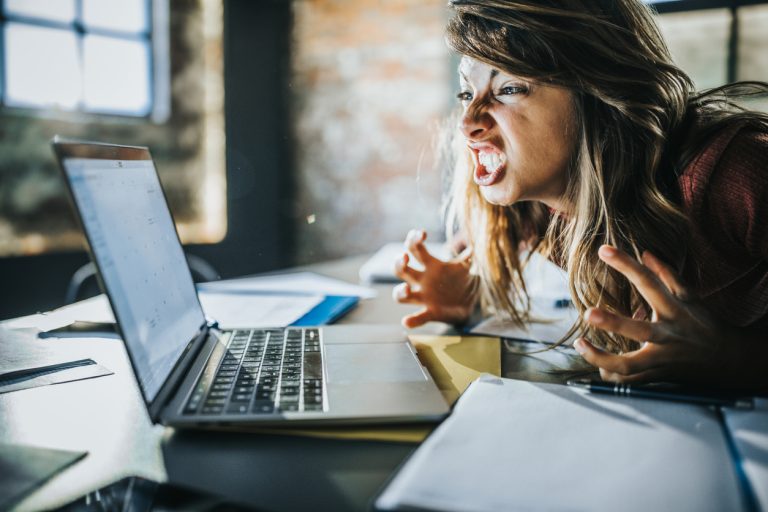 Frustrated woman received a problematic e-mail over computer. Angry freelance worker feeling displeased after reading an e-mail on a computer.