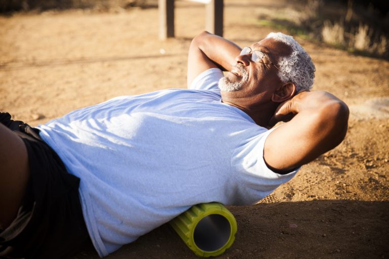 Senior Black Man Using Foam Roller An attractive senior black man gets some back relief by using a foam roller