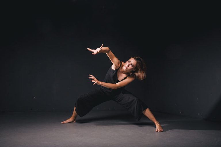 Portrait Portrait of a beautiful woman dancing on black background. Ballet and contemporary dancer dancing on dark backdrop. Contemporary Art. Plastic and flexible girl in black clothes posing on a black wall.