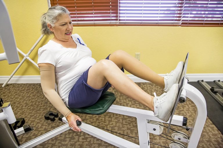 Caucasian senior woman works hard on leg press at rehab Caucasian senior woman using leg press as part of her rehabilitation. She is at the physical therapist and using the lower body machine to build strength in her leg muscles. She is wearing shorts