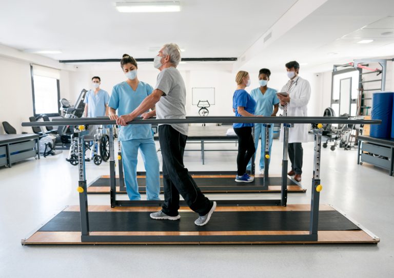 Group of doctors and patients in a physiotherapy center wearing facemasks Group of doctors and patients in a physiotherapy center wearing facemasks - COVID-19 pandemic lifestyle concepts