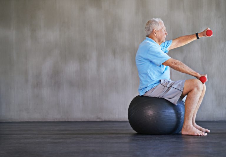 Combat aging one kilo at a time Shot of an elderly man using weights while sitting on a swiss ball