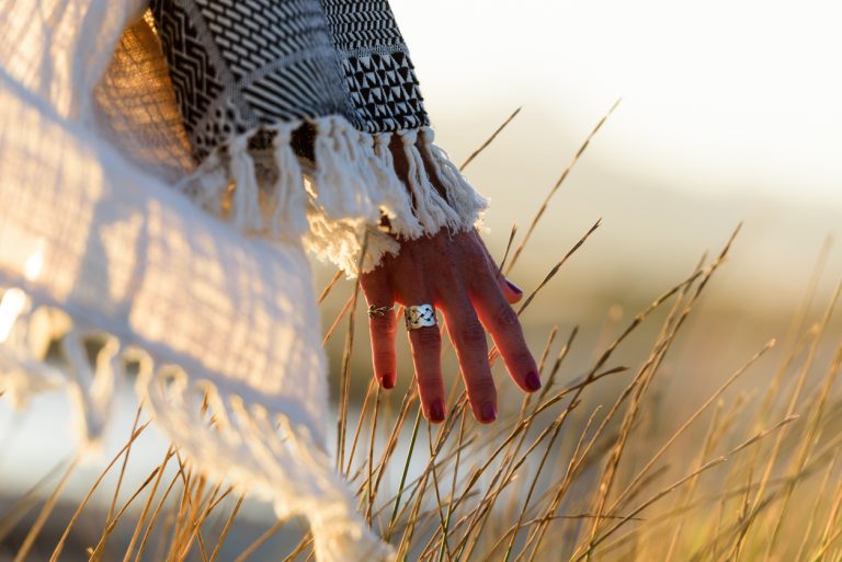 Woman hand caressing grass Woman hand caressing grass in nature near the sea at sunset