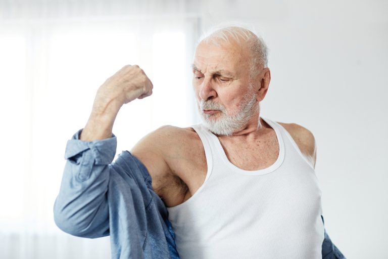 Portrait of a senior man showing biceps and strength