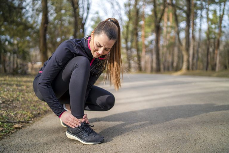 Runner girl is holding her injured leg Woman sprained her ankle while running in park