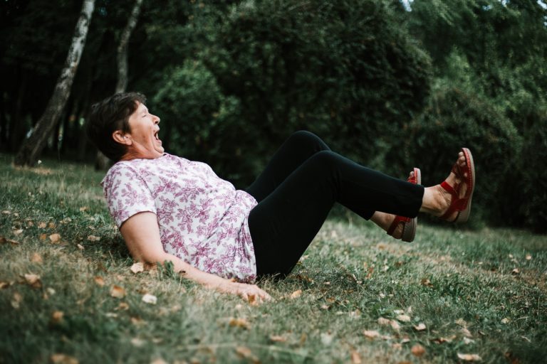 Senior woman felt on the ground Hurt senior woman felt on the ground on her back with both legs in the air outdoors - Cute old lady injured in the grass after slipping off her feet in the park - Weak elderly person suffering small accident in nature