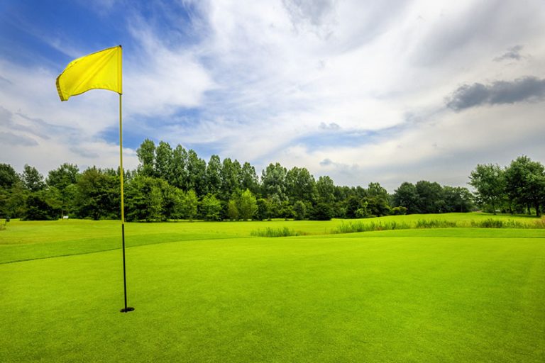18th hole on golf course golf course with yellow flag on 18th hole at cloudy sky