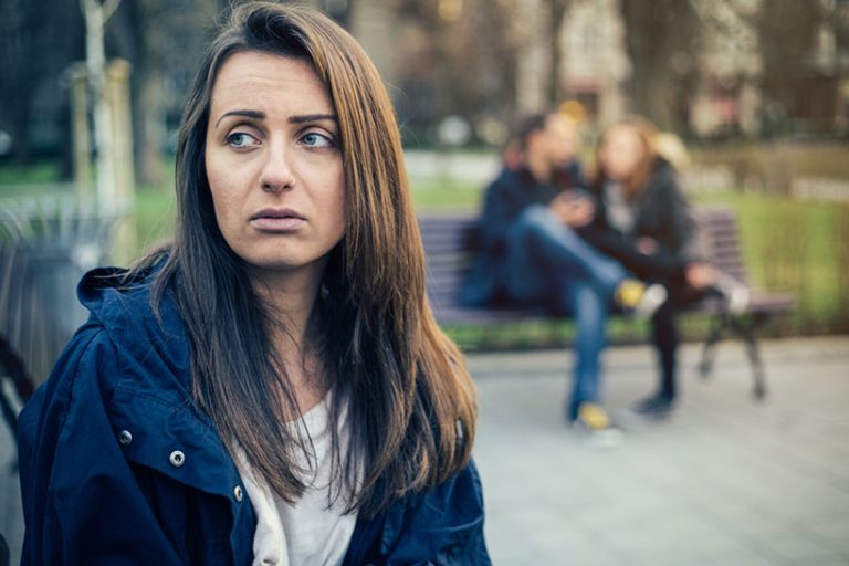 Depression Lonely single girl feeling depressed because of a happy couple laughing on the next bench.