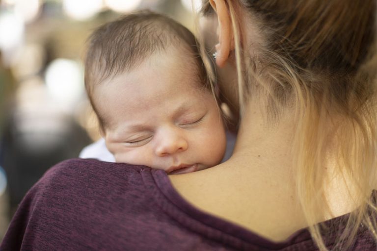 Cozy nap Portrait of young mother holding a newborn baby boy in the public park.