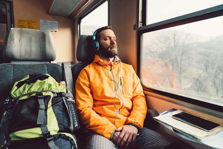 Relaxed man in the train Young man with headphones napping in the train