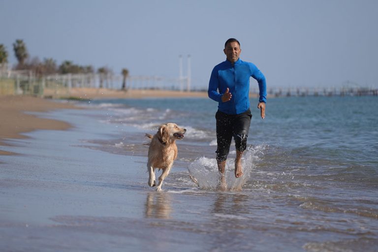 Man running on the beach with his dog Man running on the beach with his dog