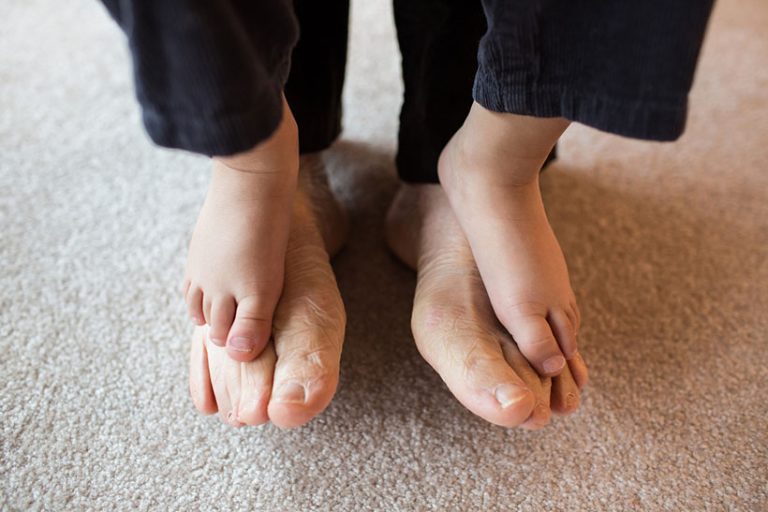 Grandson standing on grandfather's bare feet Close up of Grandson's feet on top of his Grandfather's feet