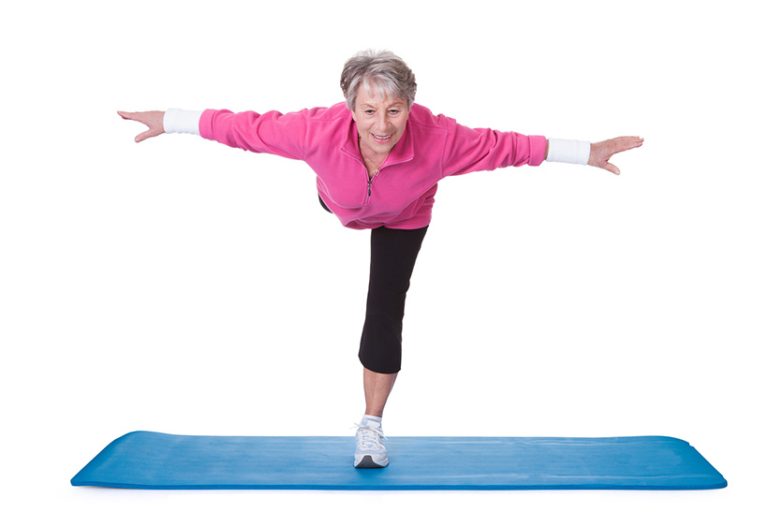 Senior Woman Standing On One Leg And Exercising Senior Woman Standing On One Leg And Exercising Over White Background