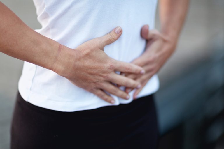 Breathing exercise: feeling the breath with hands on abdomen Close up of a woman holding the hands on abdomen