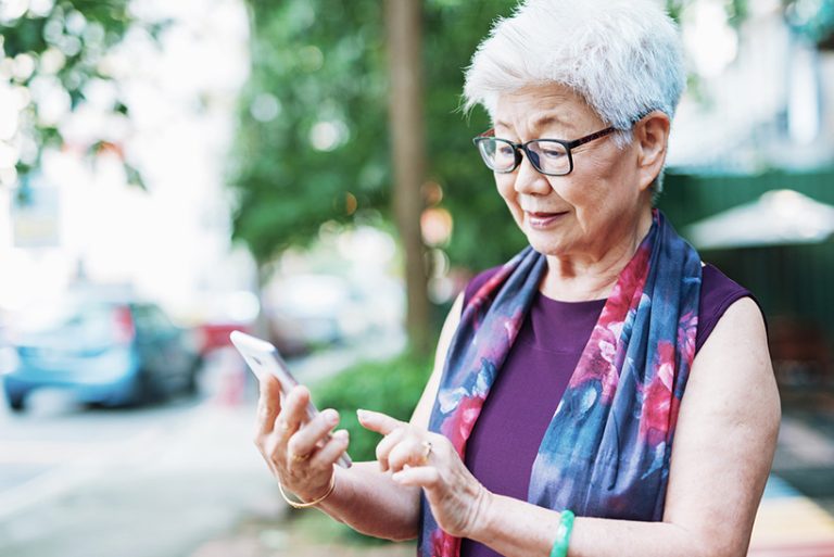 Senior woman in the city using phone to call taxi Portrait of seniror Chinese woman