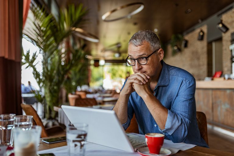 Sometimes the stress is just too much Contemplating businessman in the restaurant feeling sad. Full concentration on work. Confident mature man working on laptop while sitting at his working place in office. Tired manager sitting in restaurant surrounded with coffee and laptop computer having tired look