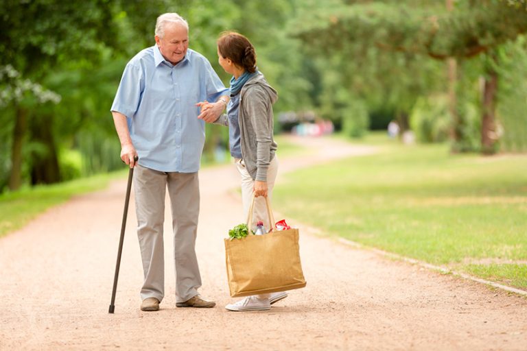 Caregiver – woman helping senior man with shopping Senior man with caregiver going shopping at market place