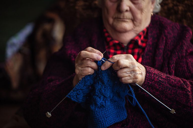 Senior woman knits garments The old woman sits at home and knits garments