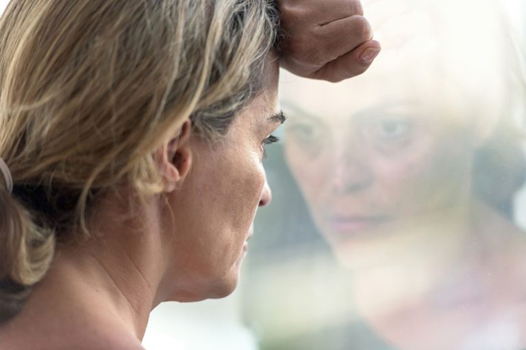 Pensive woman Pensive hispanic mature woman looking through a window