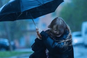 Vrouw loopt door harde regen en wind met een paraplu, worstelend maar volhoudend tegen de omstandigheden