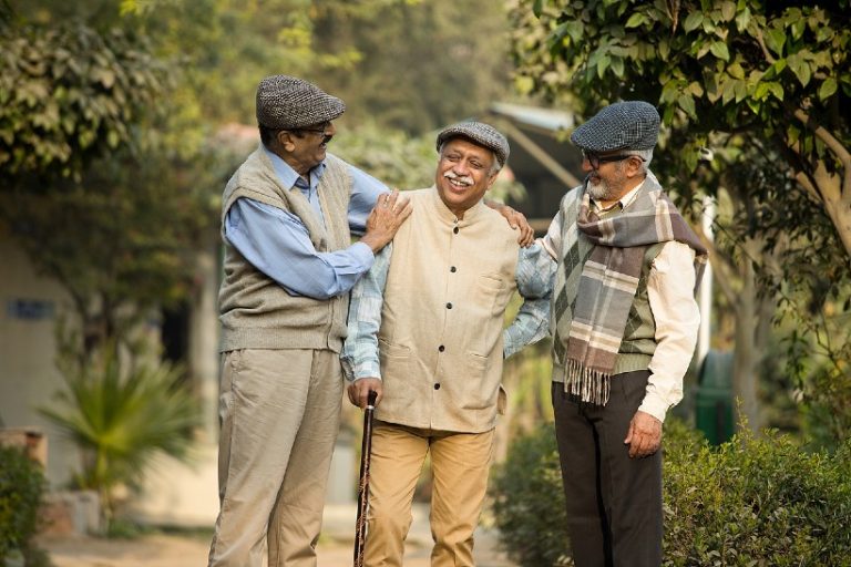 19-20-Acceptance and commitment therapy (ACT) sluit goed aan bij ouderen met rugpijn-iStock-1455405944 Drie oudere mannen wandelen samen buiten en praten met een glimlach, symbool voor verbinding en acceptatie bij omgaan met chronische pijn.
