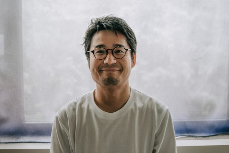 Portret van een man met bril die rustig in de camera kijkt, passend bij het thema mindfulness en aandacht.